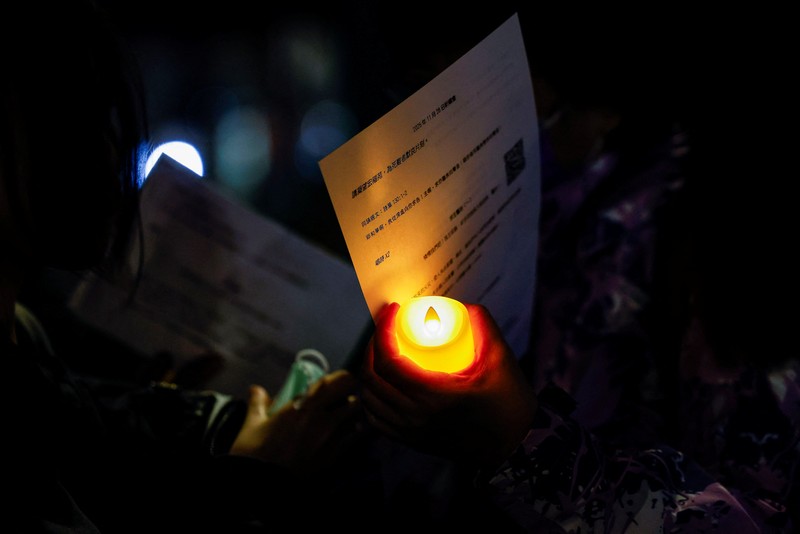 Orang-orang memegang kertas doa saat berkumpul, setelah kebakaran mematikan di kompleks perumahan Wang Fuk Court di Tai Po, Hong Kong, Cina, 28 November 2025. (REUTERS/Maxim Shemetov)
