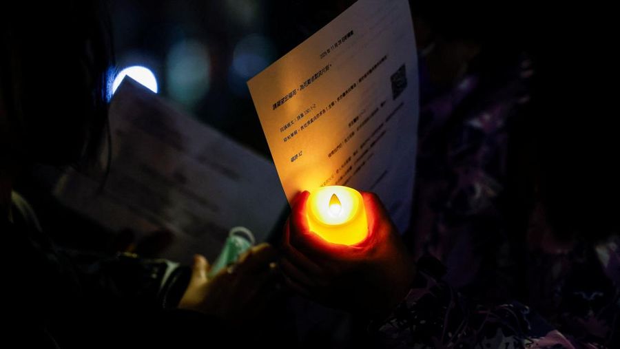 Orang-orang memegang kertas doa saat berkumpul, setelah kebakaran mematikan di kompleks perumahan Wang Fuk Court di Tai Po, Hong Kong, Cina, 28 November 2025. (REUTERS/Maxim Shemetov)