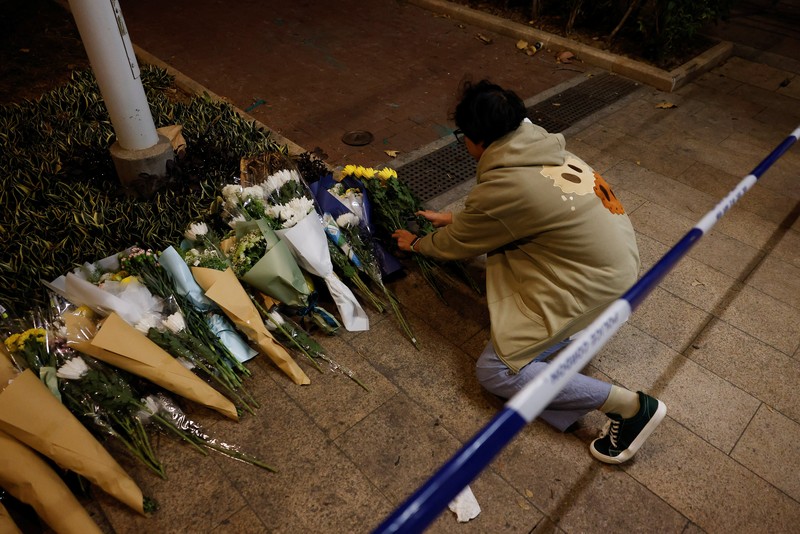 Orang-orang memegang kertas doa saat berkumpul, setelah kebakaran mematikan di kompleks perumahan Wang Fuk Court di Tai Po, Hong Kong, Cina, 28 November 2025. (REUTERS/Maxim Shemetov)