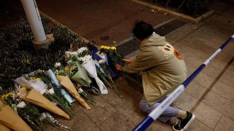 Orang-orang memegang kertas doa saat berkumpul, setelah kebakaran mematikan di kompleks perumahan Wang Fuk Court di Tai Po, Hong Kong, Cina, 28 November 2025. (REUTERS/Maxim Shemetov)