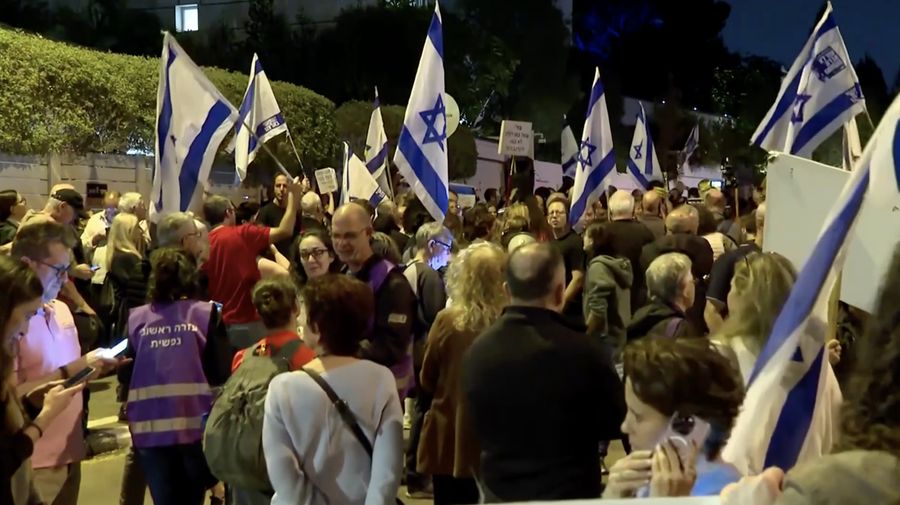 Para pengunjuk rasa berkumpul di luar kediaman pribadi Presiden Israel Isaac Herzog pada Minggu (30/11/2025). (Tangkapan Layar Video Reuters/)