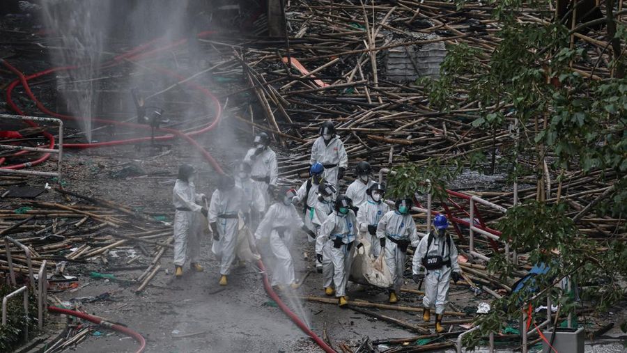 Petugas polisi membawa jenazah korban yang ditemukan dari blok perumahan yang rusak akibat kebakaran di kompleks perumahan Wang Fuk Court setelah kebakaran mematikan, di Tai Po, Hong Kong, Tiongkok, 1 Desember 2025. (REUTERS/Maxim Shemetov)