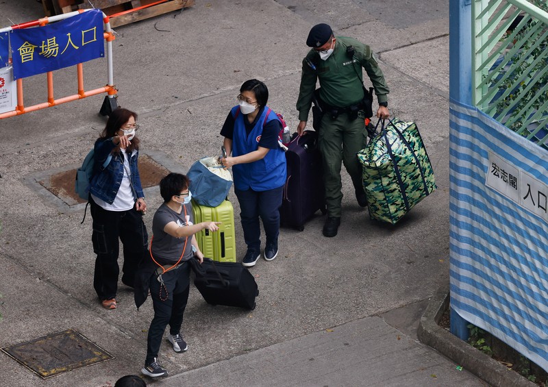 Seorang penghuni Wang Chi House, satu-satunya bangunan yang tidak terkena dampak langsung kebakaran mematikan di kompleks perumahan Wang Fuk Court, menggulingkan kopernya melintasi jalan setelah mengambil barang-barang miliknya, di Tai Po, Hong Kong, Tiongkok, 3 Desember 2025. (REUTERS/Maxim Shemetov)