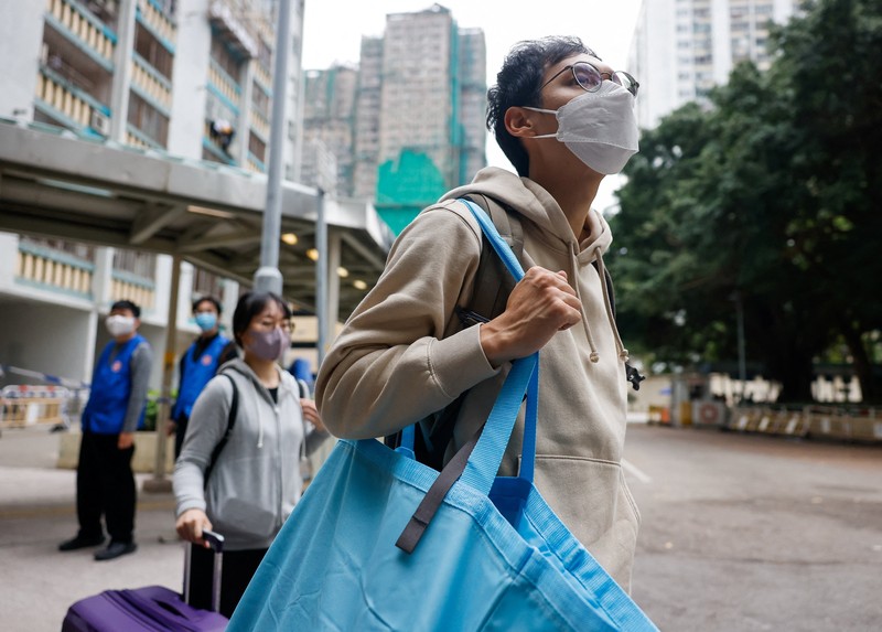 Seorang penghuni Wang Chi House, satu-satunya bangunan yang tidak terkena dampak langsung kebakaran mematikan di kompleks perumahan Wang Fuk Court, menggulingkan kopernya melintasi jalan setelah mengambil barang-barang miliknya, di Tai Po, Hong Kong, Tiongkok, 3 Desember 2025. (REUTERS/Maxim Shemetov)