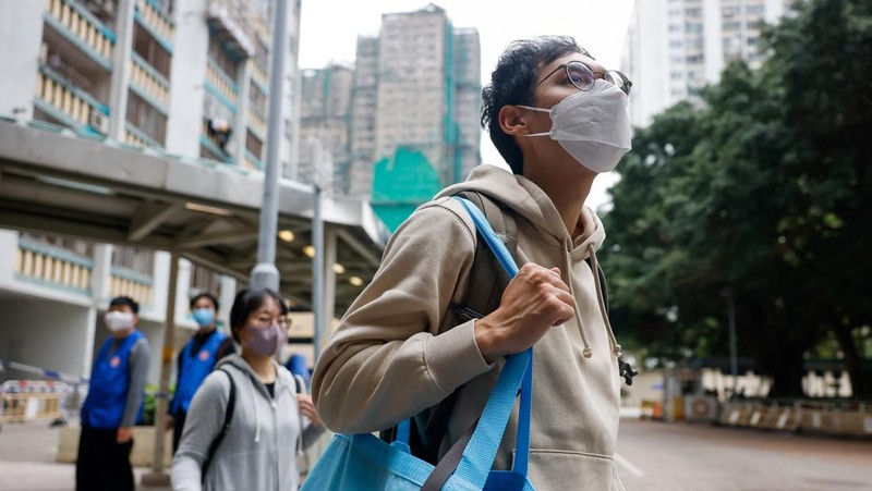 Seorang penghuni Wang Chi House, satu-satunya bangunan yang tidak terkena dampak langsung kebakaran mematikan di kompleks perumahan Wang Fuk Court, menggulingkan kopernya melintasi jalan setelah mengambil barang-barang miliknya, di Tai Po, Hong Kong, Tiongkok, 3 Desember 2025. (REUTERS/Maxim Shemetov)