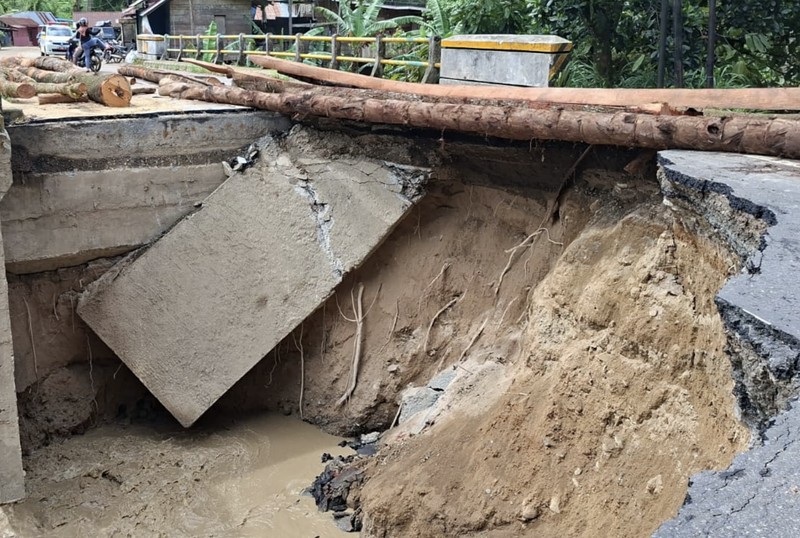 Perbaikan darurat infrastruktur jembatan yang putus diterjang banjir di Kabupaten Agam, Rabu (3/12). Perbaikan darurat dilakukan dengan balok pohon kelapa sehingga akses jalan dapat dilalui paling tidak dengan kendaraan roda dua. (Dok. BNPB)
