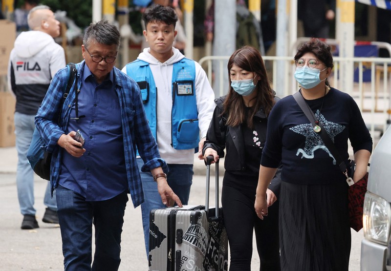 Seorang penghuni Wang Chi House, satu-satunya bangunan yang tidak terkena dampak langsung kebakaran mematikan di kompleks perumahan Wang Fuk Court, menggulingkan kopernya melintasi jalan setelah mengambil barang-barang miliknya, di Tai Po, Hong Kong, Tiongkok, 3 Desember 2025. (REUTERS/Maxim Shemetov)
