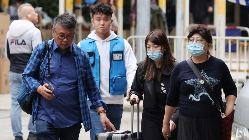 Seorang penghuni Wang Chi House, satu-satunya bangunan yang tidak terkena dampak langsung kebakaran mematikan di kompleks perumahan Wang Fuk Court, menggulingkan kopernya melintasi jalan setelah mengambil barang-barang miliknya, di Tai Po, Hong Kong, Tiongkok, 3 Desember 2025. (REUTERS/Maxim Shemetov)