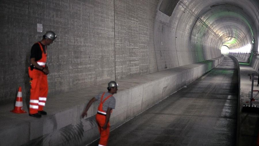 Para pekerja berdiri di salah satu terowongan akses dasar Gotthard saat peresmian pemasangan peralatan kereta api pada 2 September 2011 di Erstfeld, Swiss tengah. (Photo by FABRICE COFFRINI / AFP/File Foto)