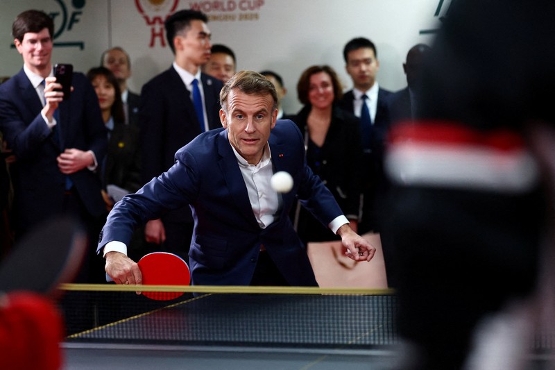 Presiden Prancis Emmanuel Macron bermain tenis meja dengan pemain tenis meja Tiongkok di Universitas Sichuan di Chengdu, provinsi Sichuan, sebagai bagian dari kunjungan tiga hari ke Tiongkok, 5 Desember 2025. (REUTERS/Sarah Meyssonnier/Pool)