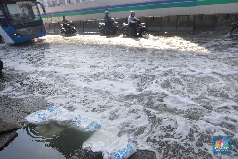 Sejumlah kendaraan roda dua dan roda empat melintasi banjir rob yang menggenangi Jalan RE Martadinata, Tanjung Priok, Jakarta Utara, Jumat (05/12/2025). (CNBC Indonesia/Muhammad Sabki)