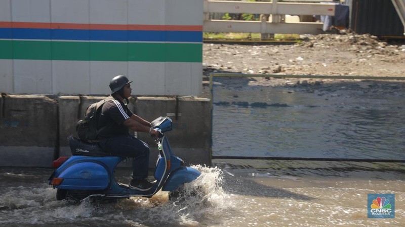 Sejumlah kendaraan roda dua dan roda empat melintasi banjir rob yang menggenangi Jalan RE Martadinata, Tanjung Priok, Jakarta Utara, Jumat (05/12/2025). (CNBC Indonesia/Muhammad Sabki)