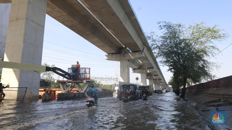 Sejumlah kendaraan roda dua dan roda empat melintasi banjir rob yang menggenangi Jalan RE Martadinata, Tanjung Priok, Jakarta Utara, Jumat (05/12/2025). (CNBC Indonesia/Muhammad Sabki)