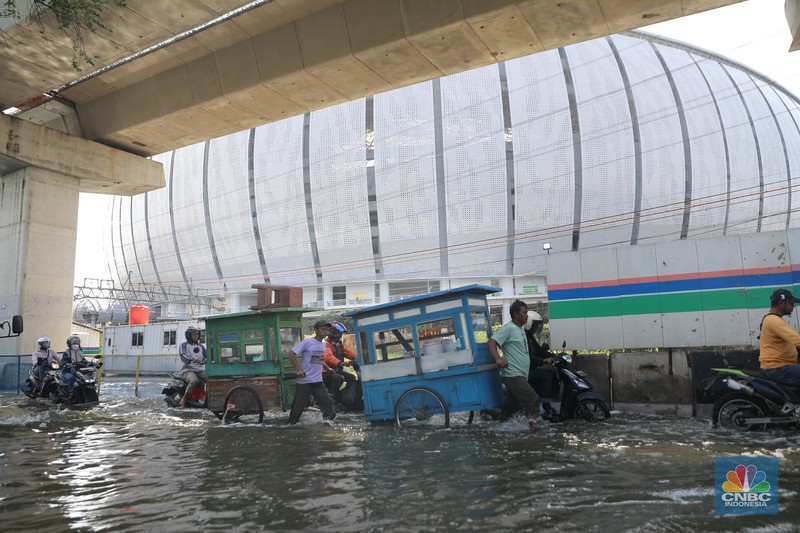 Sejumlah kendaraan roda dua dan roda empat melintasi banjir rob yang menggenangi Jalan RE Martadinata, Tanjung Priok, Jakarta Utara, Jumat (05/12/2025). (CNBC Indonesia/Muhammad Sabki)