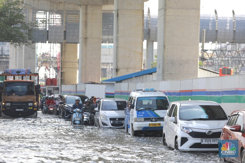 Sejumlah kendaraan roda dua dan roda empat melintasi banjir rob yang menggenangi Jalan RE Martadinata, Tanjung Priok, Jakarta Utara, Jumat (05/12/2025). (CNBC Indonesia/Muhammad Sabki)