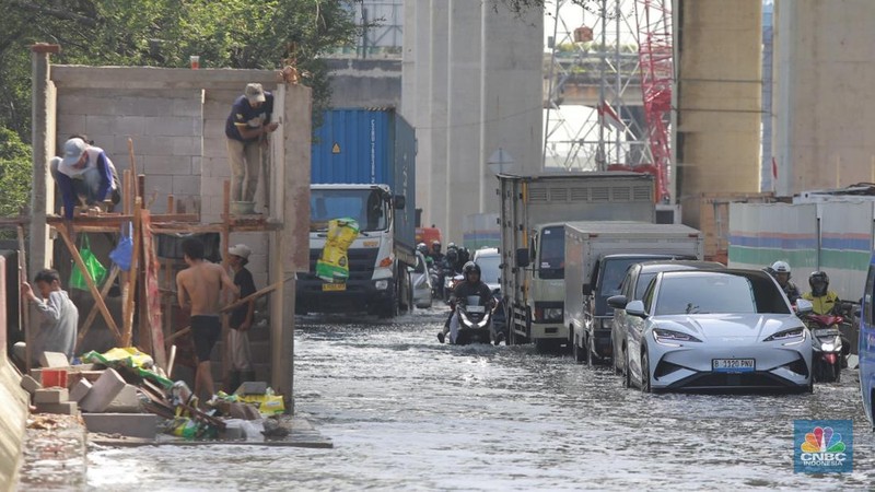 Sejumlah kendaraan roda dua dan roda empat melintasi banjir rob yang menggenangi Jalan RE Martadinata, Tanjung Priok, Jakarta Utara, Jumat (05/12/2025). (CNBC Indonesia/Muhammad Sabki)