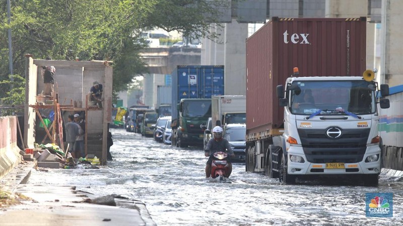 Sejumlah kendaraan roda dua dan roda empat melintasi banjir rob yang menggenangi Jalan RE Martadinata, Tanjung Priok, Jakarta Utara, Jumat (05/12/2025). (CNBC Indonesia/Muhammad Sabki)
