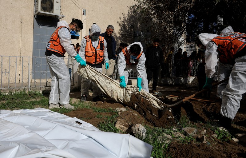 nggota Pertahanan Sipil Palestina menggali kembali jenazah orang-orang yang tewas selama perang untuk dimakamkan kembali, di Rumah Sakit Al-Ahli di Kota Gaza, Minggu (7/12/2025). (REUTERS/Dawoud Abu Alkas)