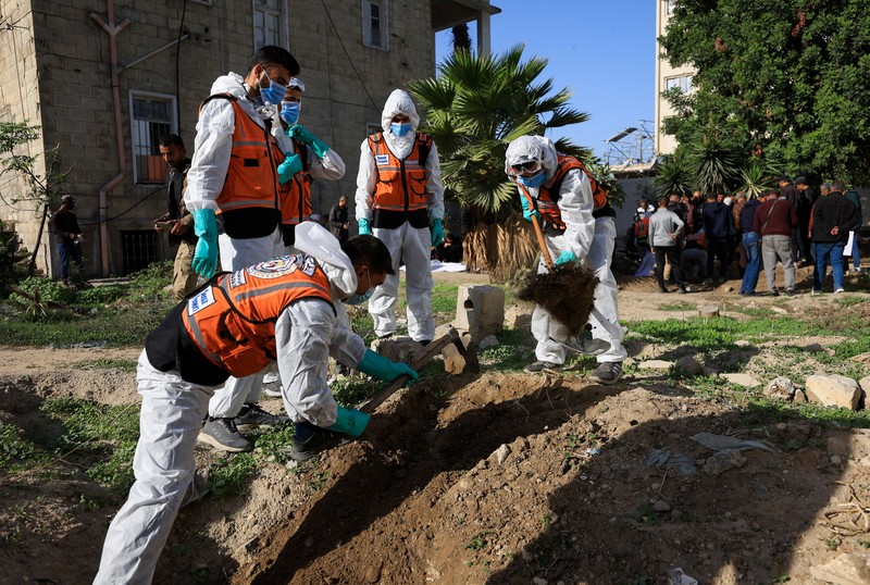 nggota Pertahanan Sipil Palestina menggali kembali jenazah orang-orang yang tewas selama perang untuk dimakamkan kembali, di Rumah Sakit Al-Ahli di Kota Gaza, Minggu (7/12/2025). (REUTERS/Dawoud Abu Alkas)