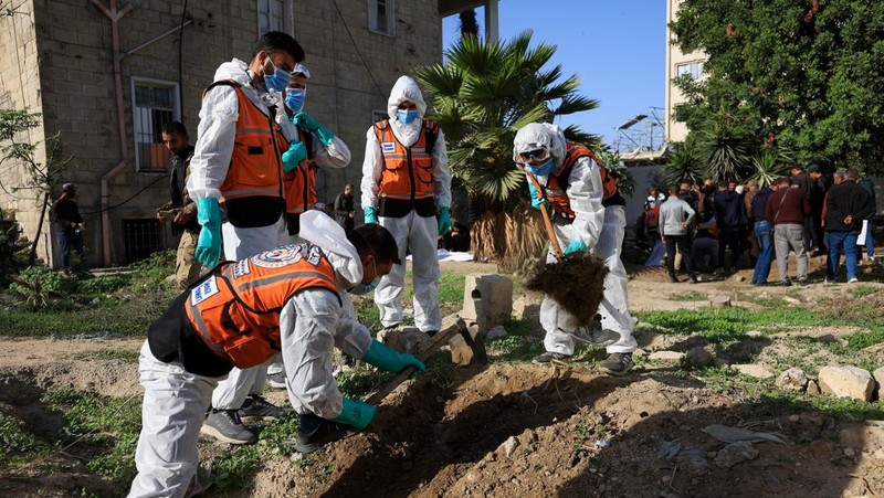 nggota Pertahanan Sipil Palestina menggali kembali jenazah orang-orang yang tewas selama perang untuk dimakamkan kembali, di Rumah Sakit Al-Ahli di Kota Gaza, Minggu (7/12/2025). (REUTERS/Dawoud Abu Alkas)