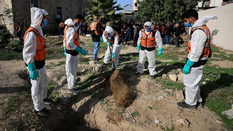 nggota Pertahanan Sipil Palestina menggali kembali jenazah orang-orang yang tewas selama perang untuk dimakamkan kembali, di Rumah Sakit Al-Ahli di Kota Gaza, Minggu (7/12/2025). (REUTERS/Dawoud Abu Alkas)