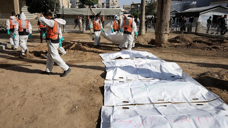 nggota Pertahanan Sipil Palestina menggali kembali jenazah orang-orang yang tewas selama perang untuk dimakamkan kembali, di Rumah Sakit Al-Ahli di Kota Gaza, Minggu (7/12/2025). (REUTERS/Dawoud Abu Alkas)
