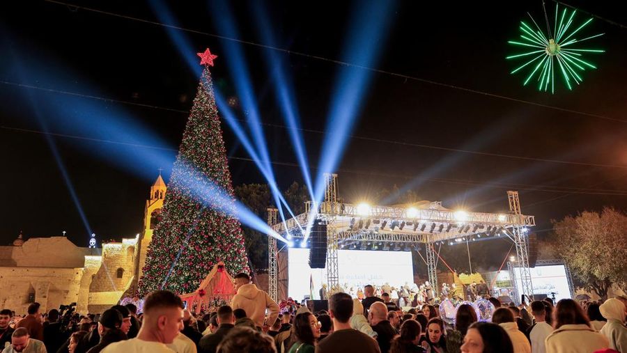 Warga Palestina melihat pohon Natal di Lapangan Manger di luar Gereja Kelahiran Yesus, Betlehem, Tepi Barat, Sabtu (6/12/2025). (REUTERS/Mussa Qawasma)