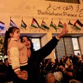Warga Palestina melihat pohon Natal di Lapangan Manger di luar Gereja Kelahiran Yesus, Betlehem, Tepi Barat, Sabtu (6/12/2025). (REUTERS/Mussa Qawasma)