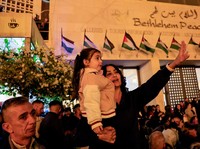 Warga Palestina melihat pohon Natal di Lapangan Manger di luar Gereja Kelahiran Yesus, Betlehem, Tepi Barat, Sabtu (6/12/2025). (REUTERS/Mussa Qawasma)
