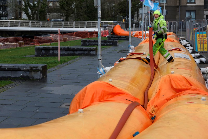 A worker holds a hose as he prepares a flood barrier defence system at the Spanish Arch, as storm named Bram approaches, in Galway, Ireland, December 9, 2025. REUTERS/Clodagh Kilcoyne