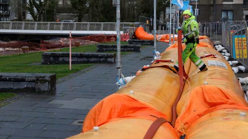 A worker holds a hose as he prepares a flood barrier defence system at the Spanish Arch, as storm named Bram approaches, in Galway, Ireland, December 9, 2025. REUTERS/Clodagh Kilcoyne