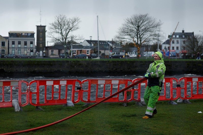 A worker holds a hose as he prepares a flood barrier defence system at the Spanish Arch, as storm named Bram approaches, in Galway, Ireland, December 9, 2025. REUTERS/Clodagh Kilcoyne