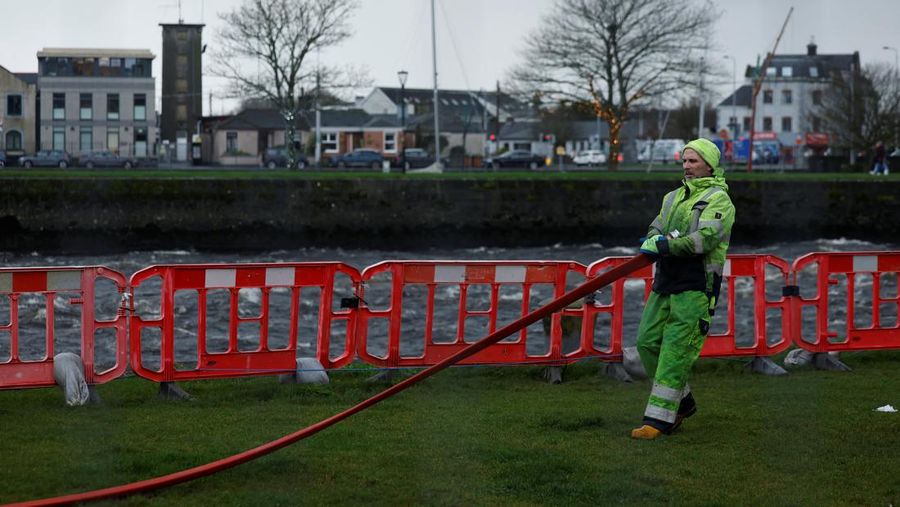 A worker holds a hose as he prepares a flood barrier defence system at the Spanish Arch, as storm named Bram approaches, in Galway, Ireland, December 9, 2025. REUTERS/Clodagh Kilcoyne