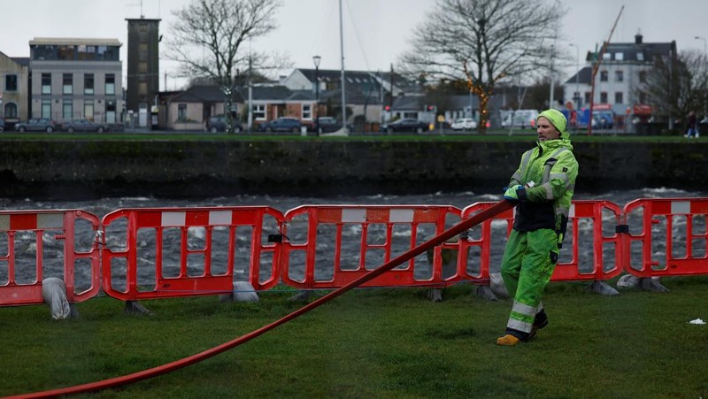 A worker holds a hose as he prepares a flood barrier defence system at the Spanish Arch, as storm named Bram approaches, in Galway, Ireland, December 9, 2025. REUTERS/Clodagh Kilcoyne