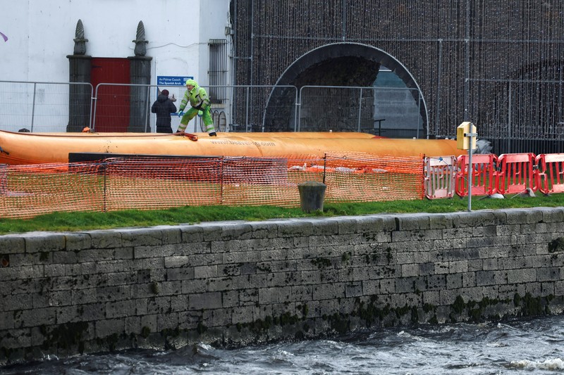 A worker holds a hose as he prepares a flood barrier defence system at the Spanish Arch, as storm named Bram approaches, in Galway, Ireland, December 9, 2025. REUTERS/Clodagh Kilcoyne