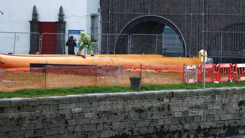 A worker holds a hose as he prepares a flood barrier defence system at the Spanish Arch, as storm named Bram approaches, in Galway, Ireland, December 9, 2025. REUTERS/Clodagh Kilcoyne