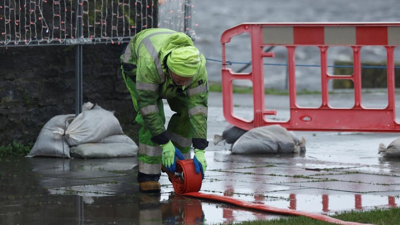 A worker holds a hose as he prepares a flood barrier defence system at the Spanish Arch, as storm named Bram approaches, in Galway, Ireland, December 9, 2025. REUTERS/Clodagh Kilcoyne