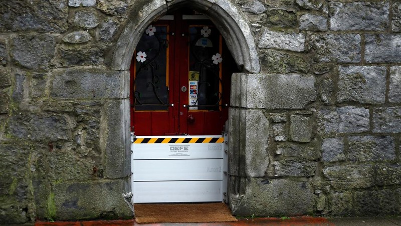 A worker holds a hose as he prepares a flood barrier defence system at the Spanish Arch, as storm named Bram approaches, in Galway, Ireland, December 9, 2025. REUTERS/Clodagh Kilcoyne