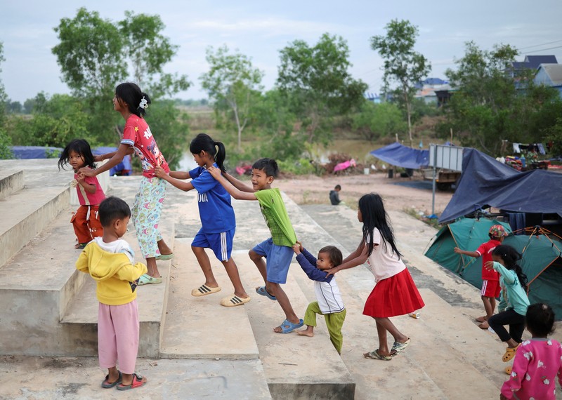 Seseorang menggendong seorang anak di kamp pengungsi setelah evakuasi, di tengah bentrokan mematikan antara Thailand dan Kamboja di sepanjang wilayah perbatasan yang disengketakan, di Srei Snam, Provinsi Siem Reap, Kamboja, 10 Desember 2025. (REUTERS/Kim Hong-Ji)