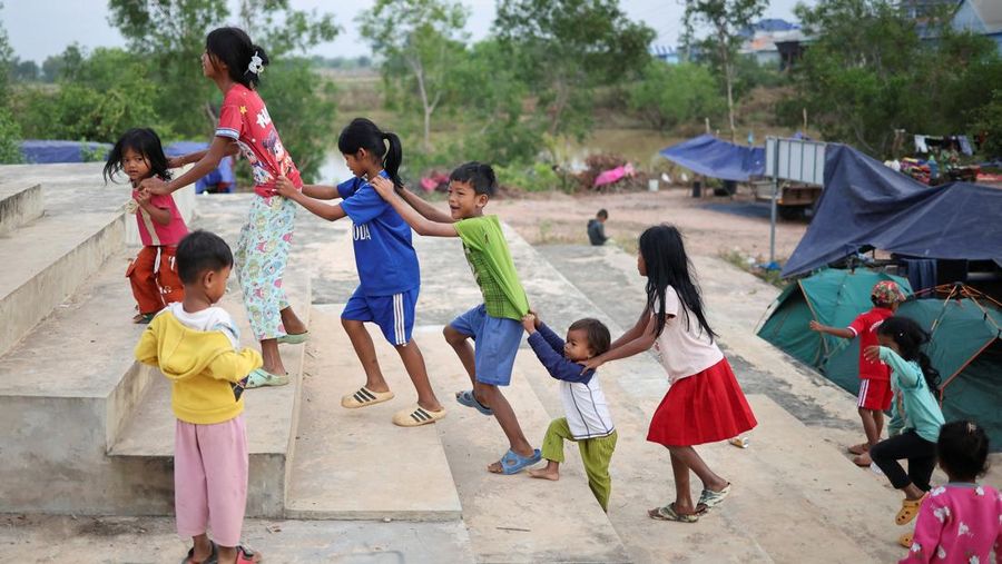 Seseorang menggendong seorang anak di kamp pengungsi setelah evakuasi, di tengah bentrokan mematikan antara Thailand dan Kamboja di sepanjang wilayah perbatasan yang disengketakan, di Srei Snam, Provinsi Siem Reap, Kamboja, 10 Desember 2025. (REUTERS/Kim Hong-Ji)