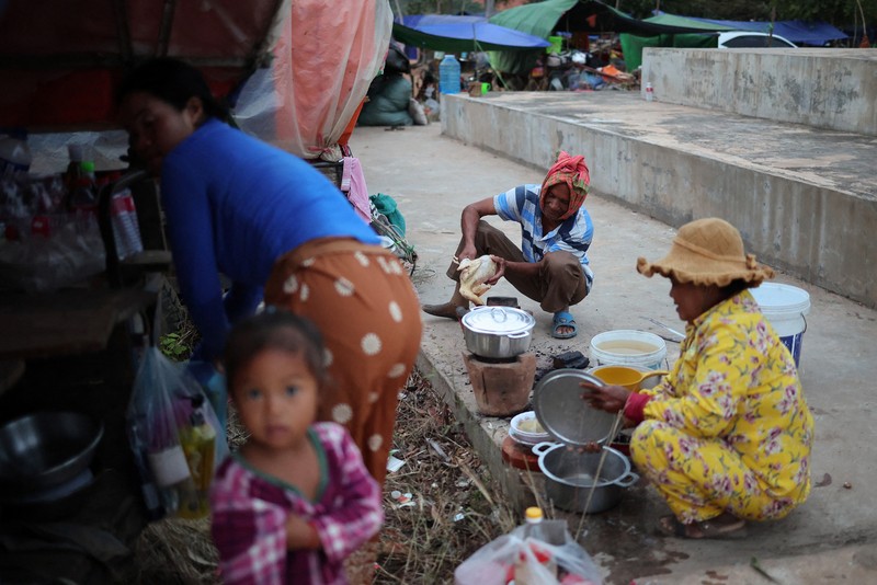 Seseorang menggendong seorang anak di kamp pengungsi setelah evakuasi, di tengah bentrokan mematikan antara Thailand dan Kamboja di sepanjang wilayah perbatasan yang disengketakan, di Srei Snam, Provinsi Siem Reap, Kamboja, 10 Desember 2025. (REUTERS/Kim Hong-Ji)