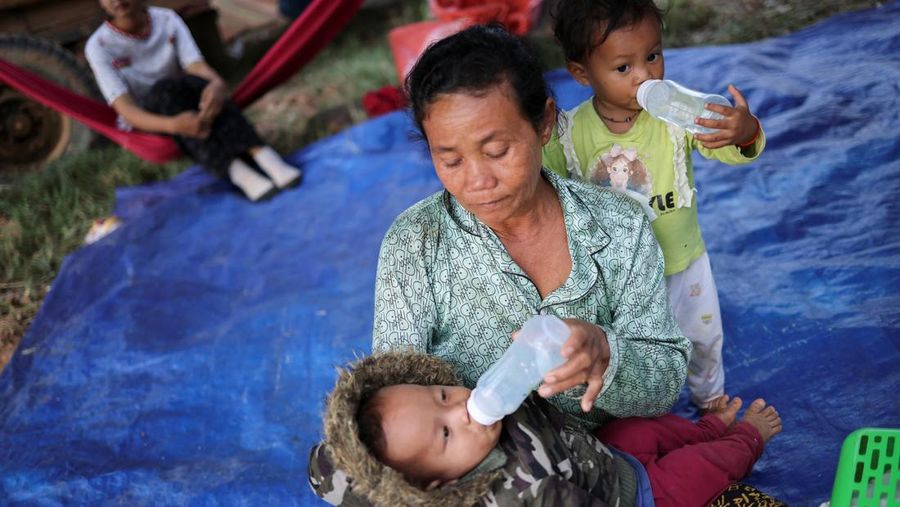 Seseorang menggendong seorang anak di kamp pengungsi setelah evakuasi, di tengah bentrokan mematikan antara Thailand dan Kamboja di sepanjang wilayah perbatasan yang disengketakan, di Srei Snam, Provinsi Siem Reap, Kamboja, 10 Desember 2025. (REUTERS/Kim Hong-Ji)