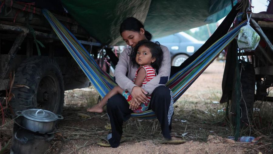 Seseorang menggendong seorang anak di kamp pengungsi setelah evakuasi, di tengah bentrokan mematikan antara Thailand dan Kamboja di sepanjang wilayah perbatasan yang disengketakan, di Srei Snam, Provinsi Siem Reap, Kamboja, 10 Desember 2025. (REUTERS/Kim Hong-Ji)