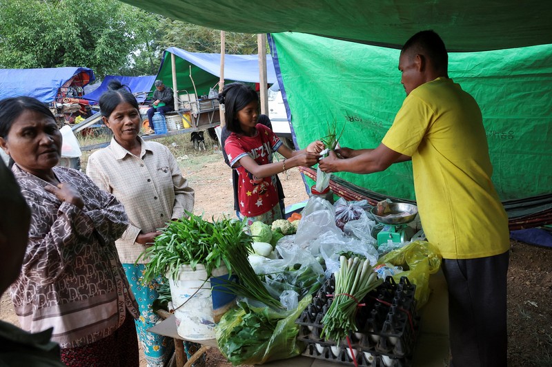 Seseorang menggendong seorang anak di kamp pengungsi setelah evakuasi, di tengah bentrokan mematikan antara Thailand dan Kamboja di sepanjang wilayah perbatasan yang disengketakan, di Srei Snam, Provinsi Siem Reap, Kamboja, 10 Desember 2025. (REUTERS/Kim Hong-Ji)