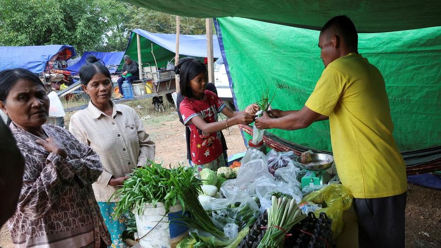 Seseorang menggendong seorang anak di kamp pengungsi setelah evakuasi, di tengah bentrokan mematikan antara Thailand dan Kamboja di sepanjang wilayah perbatasan yang disengketakan, di Srei Snam, Provinsi Siem Reap, Kamboja, 10 Desember 2025. (REUTERS/Kim Hong-Ji)