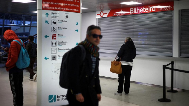 Orang-orang berjalan melewati loket tiket yang tutup di stasiun kereta api Entrecampos pada hari ketika dua serikat pekerja utama, CGTP dan UGT, menyerukan pemogokan umum sebagai protes terhadap rencana pemerintah untuk mereformasi undang-undang ketenagakerjaan, di Lisbon, Portugal, 11 Desember 2025. (REUTERS/Pedro Nunes)