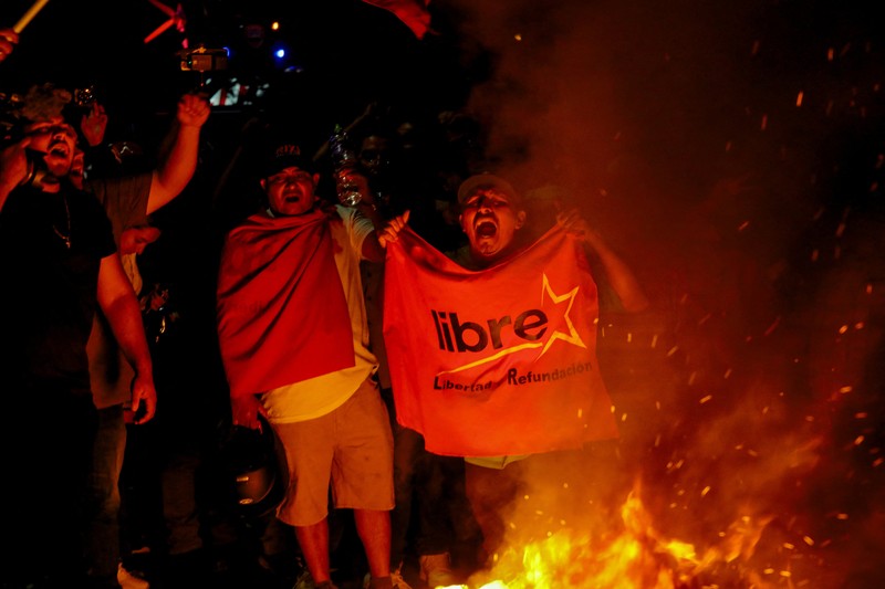 Seorang pendukung pemerintah membawa ban selama protes di luar instalasi Dewan Pemilihan Nasional (CNE) tempat penyimpanan perlengkapan pemilu, setelah Presiden Honduras Xiomara Castro mengecam apa yang disebutnya sebagai