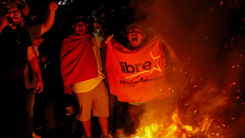 Seorang pendukung pemerintah membawa ban selama protes di luar instalasi Dewan Pemilihan Nasional (CNE) tempat penyimpanan perlengkapan pemilu, setelah Presiden Honduras Xiomara Castro mengecam apa yang disebutnya sebagai 