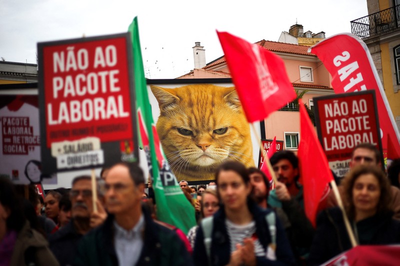 Sebuah poster promosi bergambar kucing terlihat selama demonstrasi pada hari ketika dua serikat pekerja utama, CGTP dan UGT, menyerukan pemogokan umum sebagai protes terhadap rencana pemerintah untuk mereformasi undang-undang ketenagakerjaan, di Lisbon, Portugal, 11 Desember 2025. (REUTERS/Pedro Nunes)