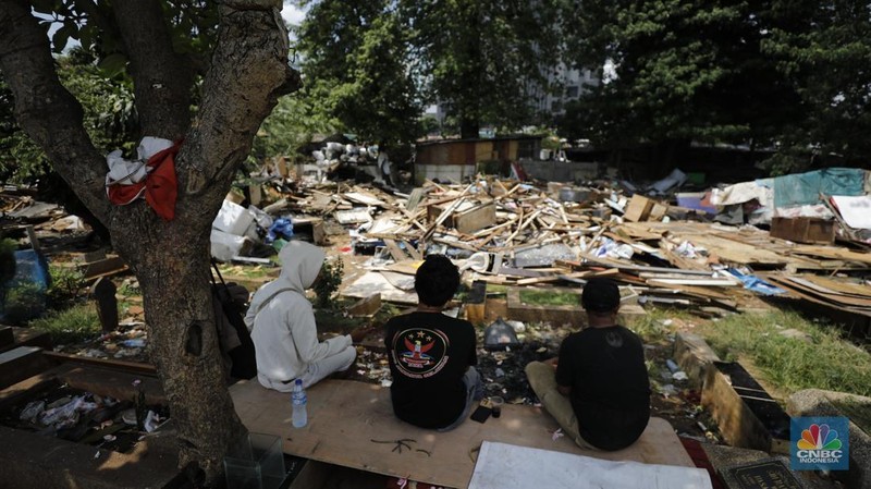 Seorang warga beraktivitas di lokasi puing-puing rumah semi permanen di TPU Menteng Pulo, Jakarta, Jumat (12/12/2025). (CNBC Indonesia/Tri Susilo)